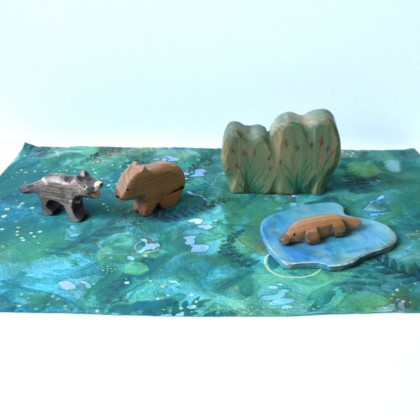 Forest themed cotton play cloth in open-ended small world play with wooden animal and scenery figurines.