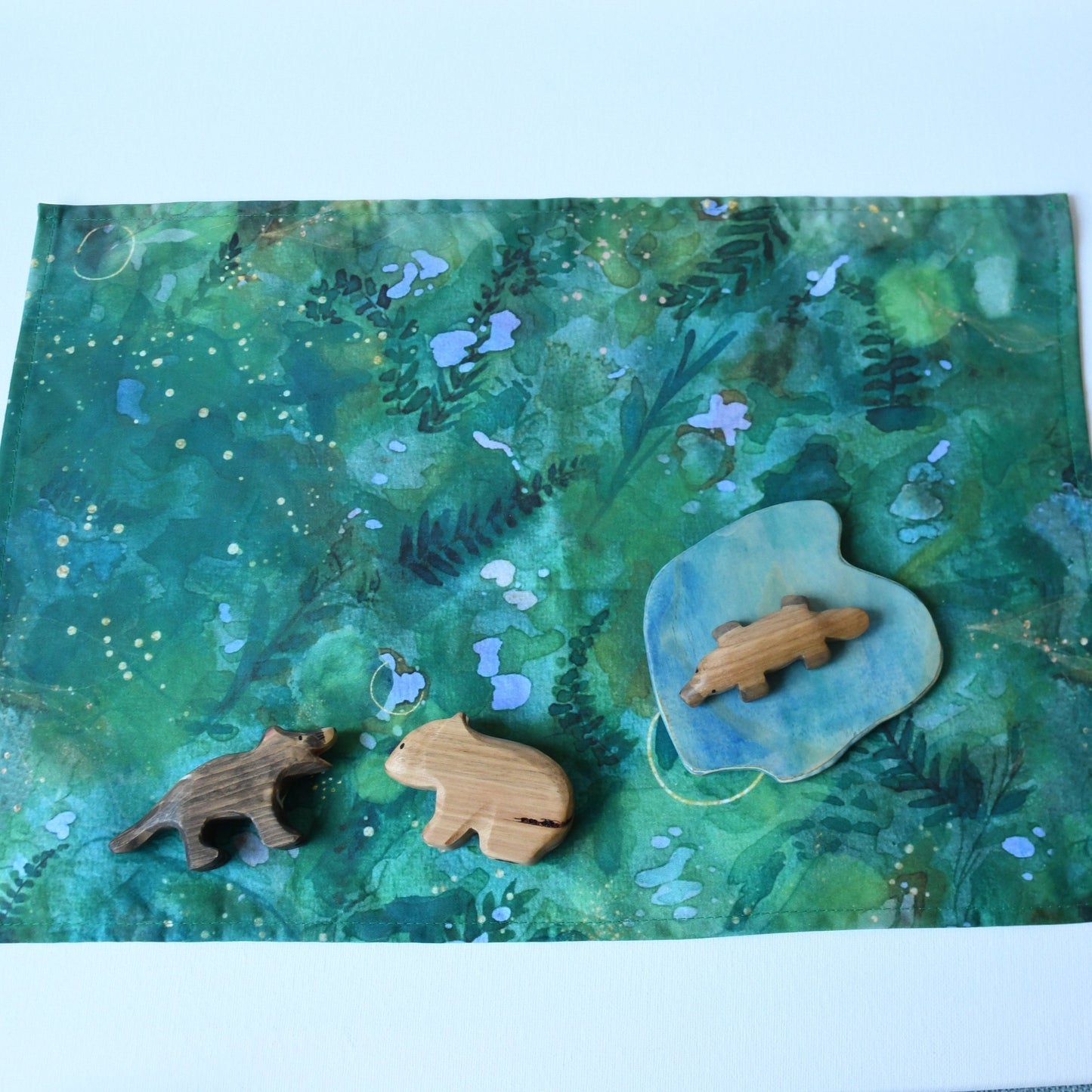 Forest themed cotton play cloth in open-ended small world play with wooden animal and scenery figurines.