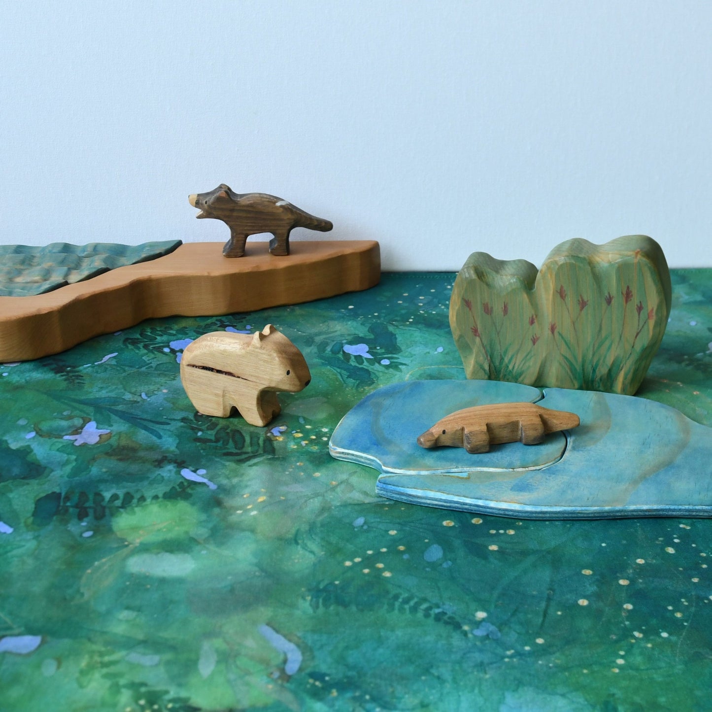 Forest themed cotton play cloth in open-ended small world play with wooden animal and scenery figurines.